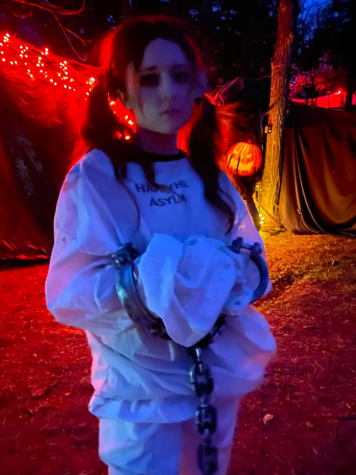 An asylum patient in a straitjacket and chains beside a flaming jack-o-lantern